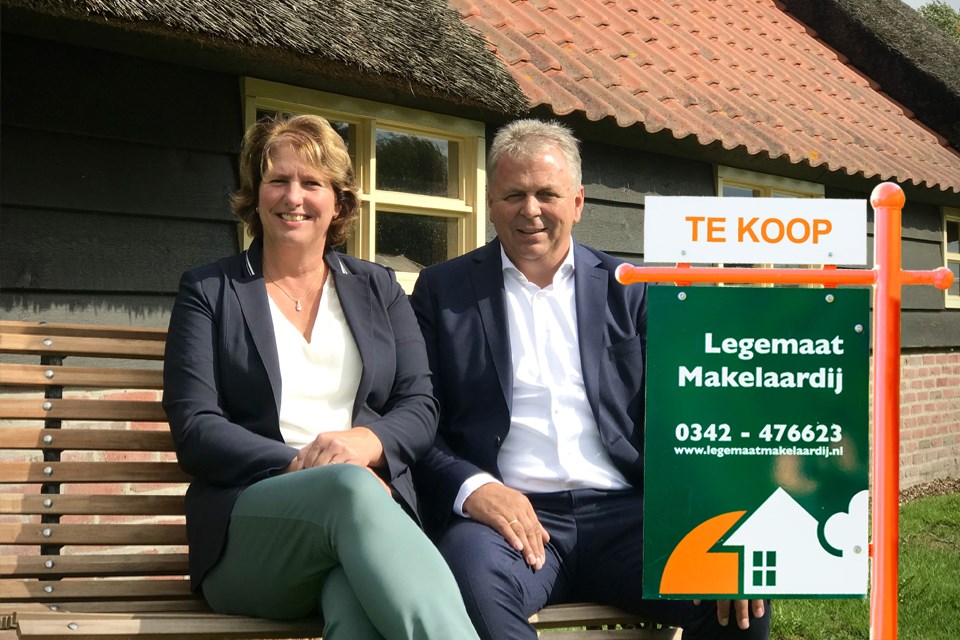 Aalt en Arina voor het pand met te koop bord