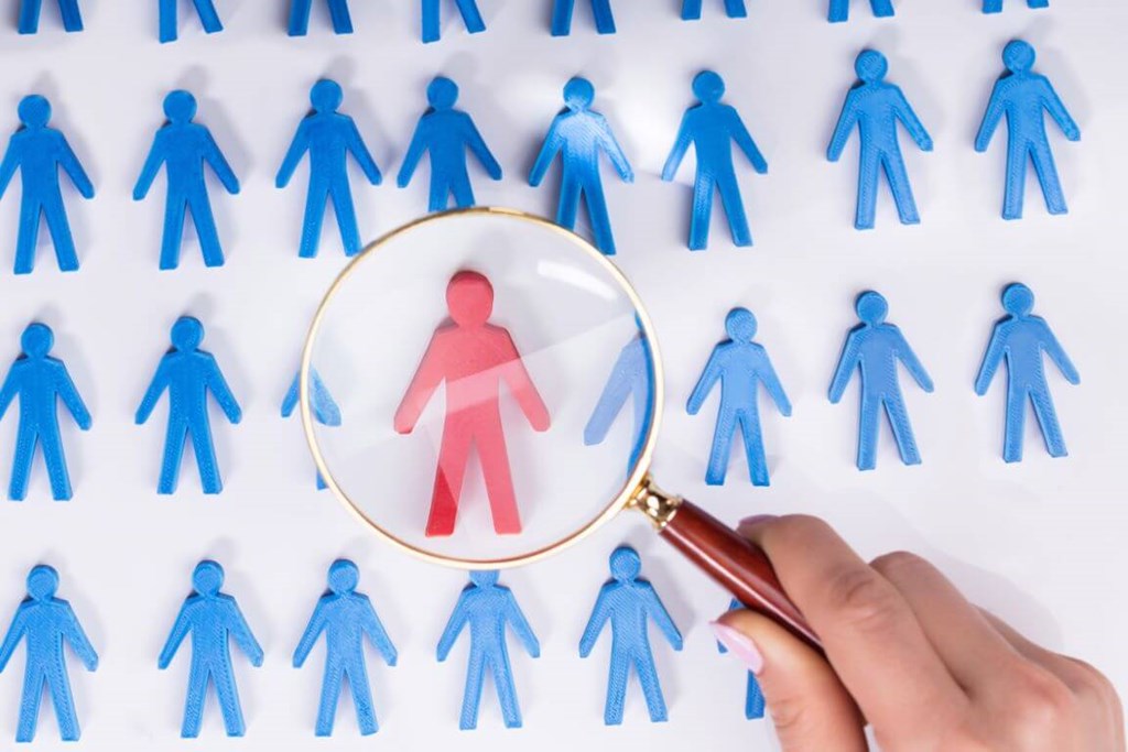 Blue people figures one red person figure in red under magnifier